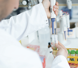 Person in Laborkittel hält Gerät in Wasserprobe